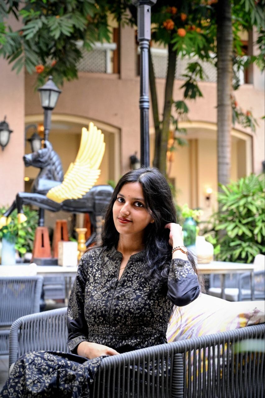 Saijal Priyadarshini Sahoo seated in a courtyard, hand in her hair