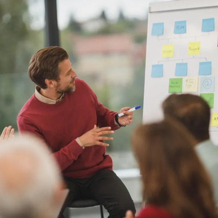 A man leading a small workshop at a whiteboard